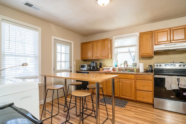 kitchen featuring visible vents, light wood-style flooring, stainless steel electric stove, under cabinet range hood, and a sink