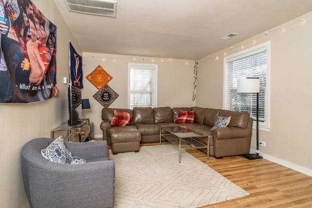 living room featuring wood finished floors, visible vents, and baseboards