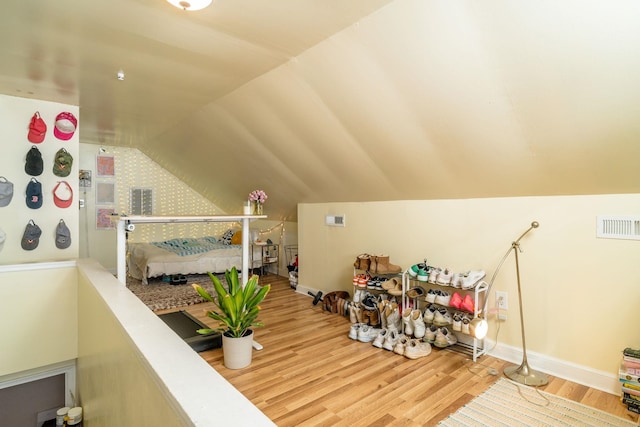 additional living space with vaulted ceiling, wood finished floors, visible vents, and baseboards