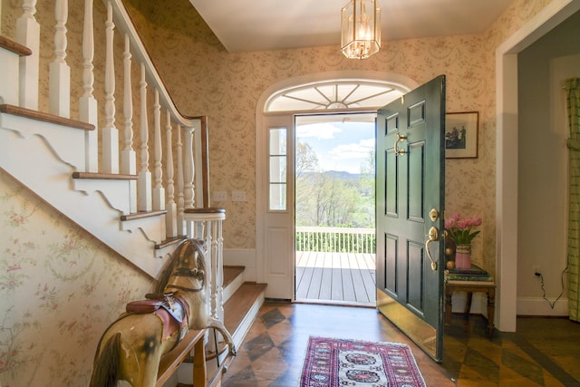 entrance foyer featuring wallpapered walls, wood finished floors, an inviting chandelier, and stairway