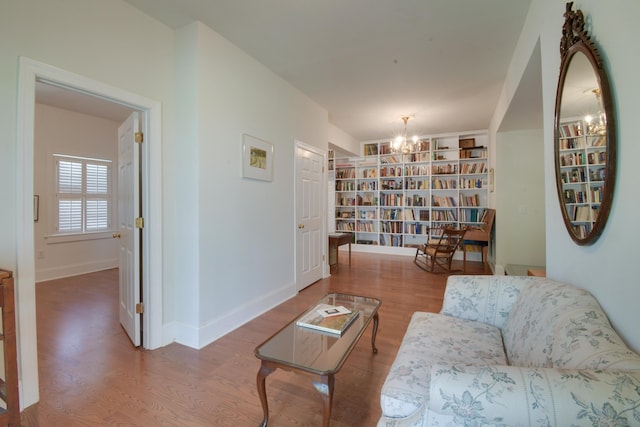 sitting room with baseboards, a chandelier, wood finished floors, and built in features