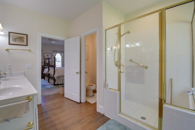 ensuite bathroom with toilet, wood finished floors, a sink, a stall shower, and ensuite bath