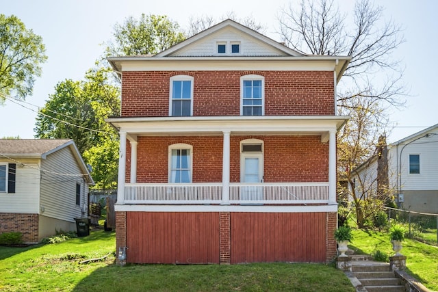 traditional style home featuring covered porch, brick siding, and a front lawn