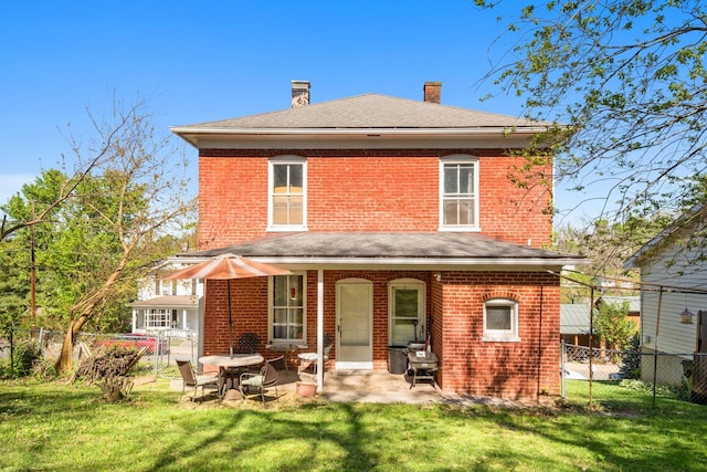back of property featuring brick siding, a fenced backyard, a lawn, and a chimney