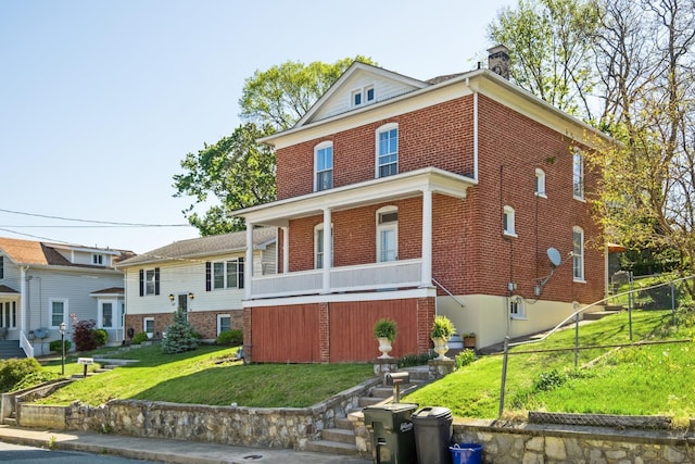 view of front of property featuring brick siding, a front lawn, fence, and a chimney
