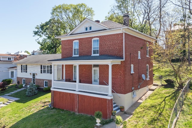 back of house with a chimney, a yard, and brick siding