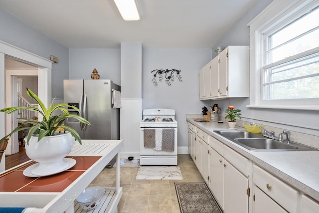 kitchen featuring a sink, light countertops, white cabinetry, baseboards, and white range with gas cooktop