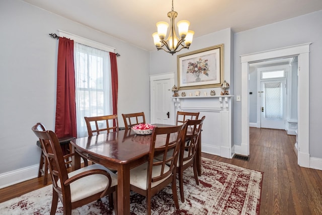 dining room with baseboards, visible vents, wood finished floors, and a notable chandelier