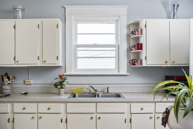 kitchen with a sink, light countertops, and white cabinets