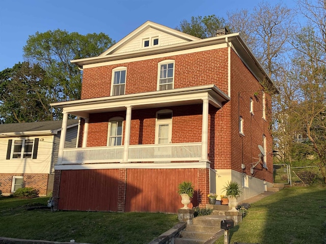 traditional style home featuring a porch, a front lawn, and brick siding