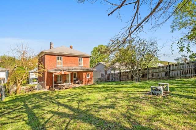 rear view of house featuring a lawn, a fenced backyard, and a chimney
