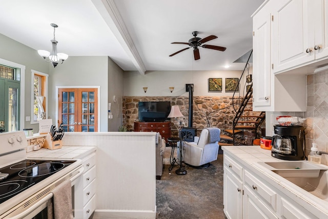 kitchen featuring hanging light fixtures, white electric range, white cabinets, tile counters, and a wood stove