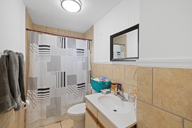 bathroom featuring tile walls, vanity, a textured ceiling, toilet, and walk in shower