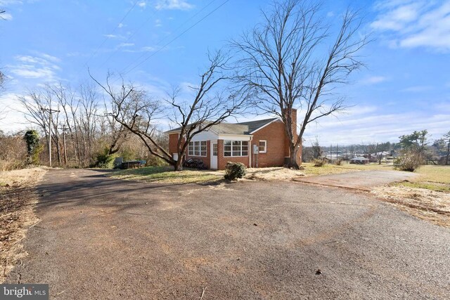 view of front of home with a front lawn, brick siding, a chimney, and entry steps