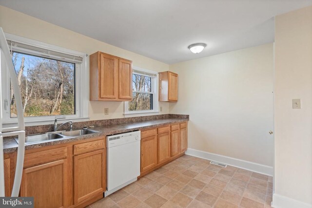 kitchen with visible vents, a sink, dark countertops, baseboards, and dishwasher