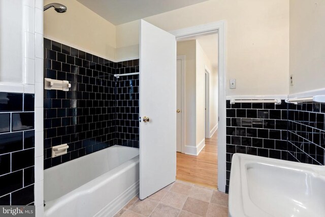 bathroom featuring tub / shower combination, a wainscoted wall, tile walls, and tile patterned flooring