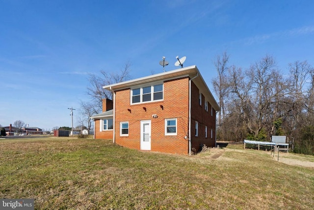 back of property with a yard and brick siding