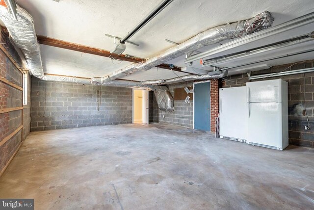 garage with a garage door opener and freestanding refrigerator