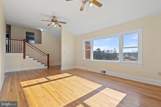 unfurnished living room with visible vents, lofted ceiling, wood finished floors, and stairway