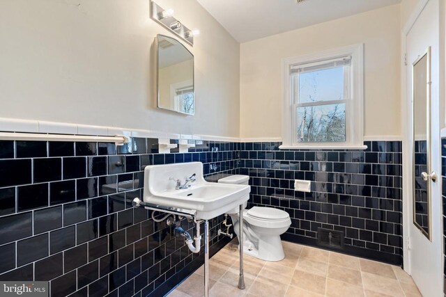 bathroom with tile patterned flooring, tile walls, toilet, and wainscoting