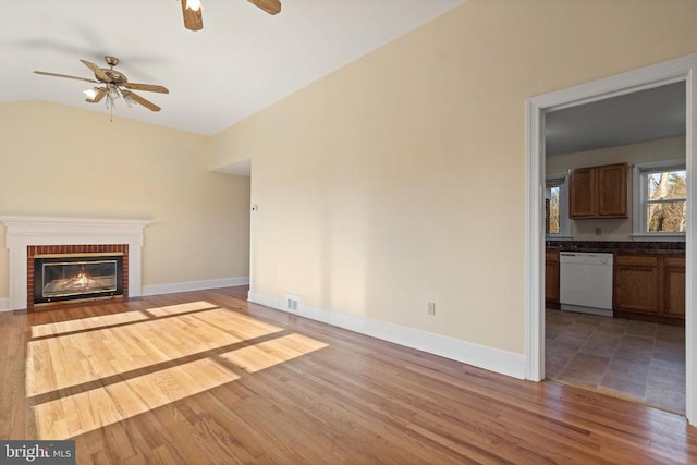 unfurnished living room featuring a fireplace, vaulted ceiling, wood finished floors, and baseboards