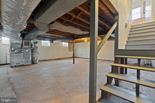 below grade area featuring heating unit, gas water heater, and stairs