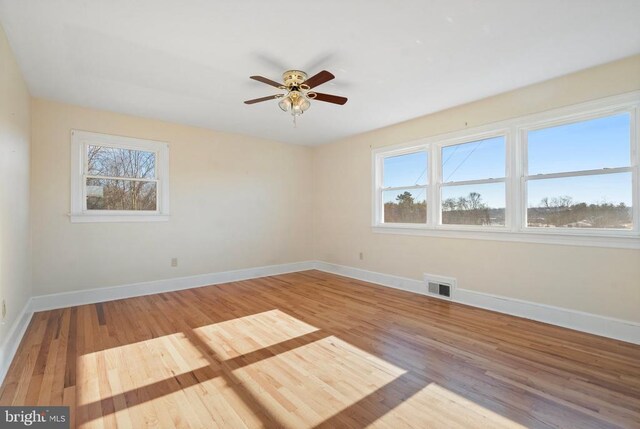 spare room with visible vents, baseboards, a healthy amount of sunlight, and wood finished floors