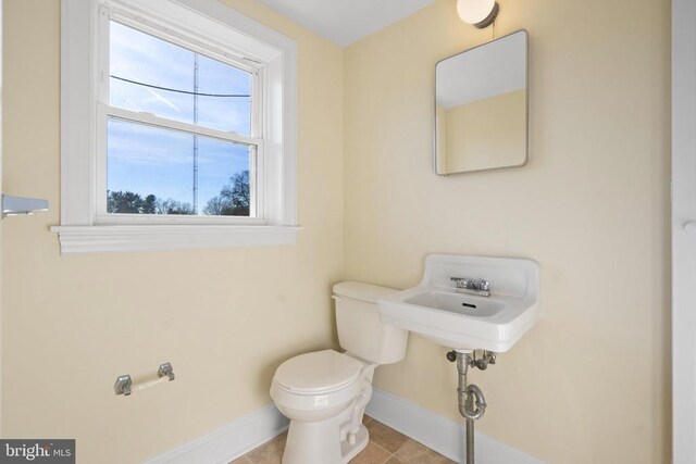 bathroom with a sink, baseboards, toilet, and tile patterned flooring