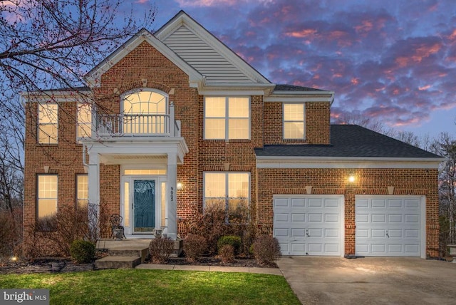 georgian-style home with roof with shingles, concrete driveway, an attached garage, a balcony, and brick siding