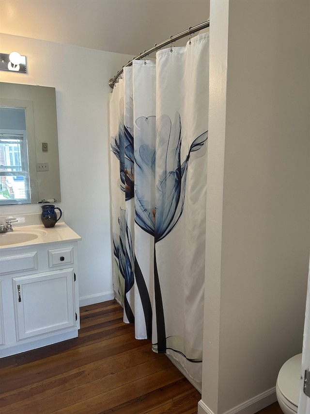 bathroom featuring vanity, toilet, baseboards, curtained shower, and wood finished floors