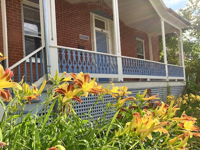 entrance to property with covered porch and brick siding
