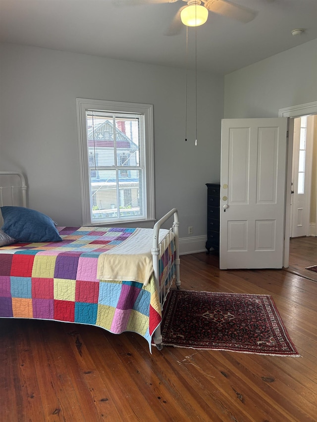 bedroom featuring baseboards, multiple windows, wood-type flooring, and ceiling fan