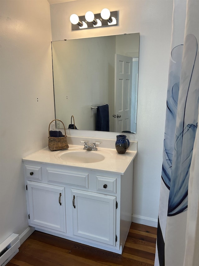 bathroom featuring vanity, baseboards, wood finished floors, and a baseboard radiator