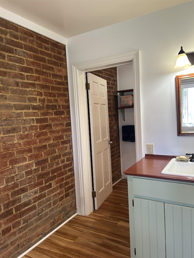 corridor featuring a sink, dark wood finished floors, and brick wall