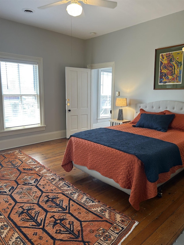 bedroom with baseboards, a ceiling fan, wood finished floors, and visible vents