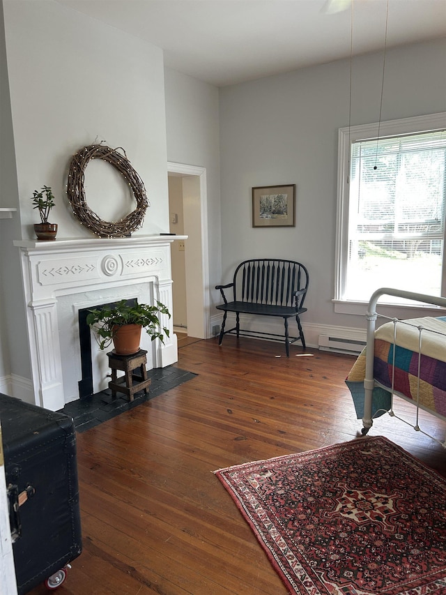 living room featuring baseboards, a fireplace with flush hearth, and hardwood / wood-style flooring