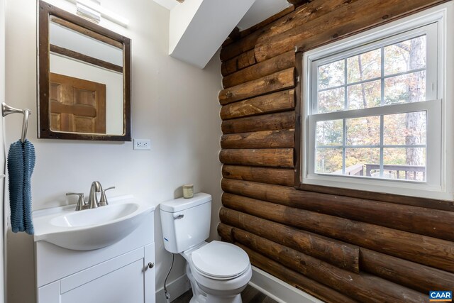 bathroom featuring vanity, log walls, and toilet