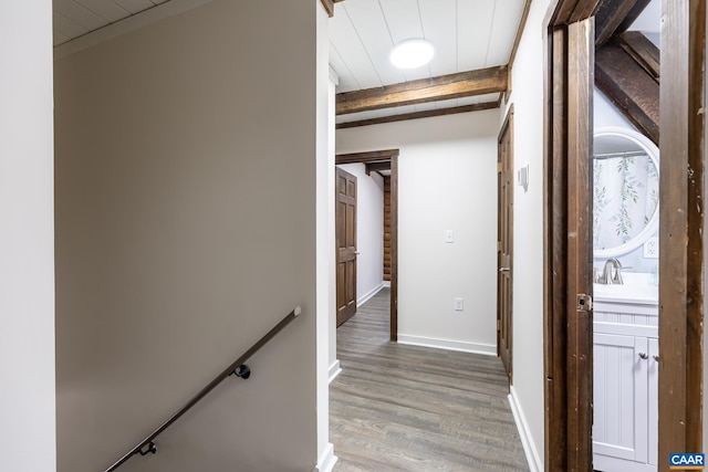 hallway featuring sink, wood-type flooring, and beamed ceiling