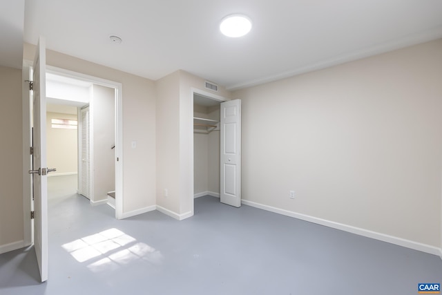 unfurnished bedroom with concrete flooring and a closet