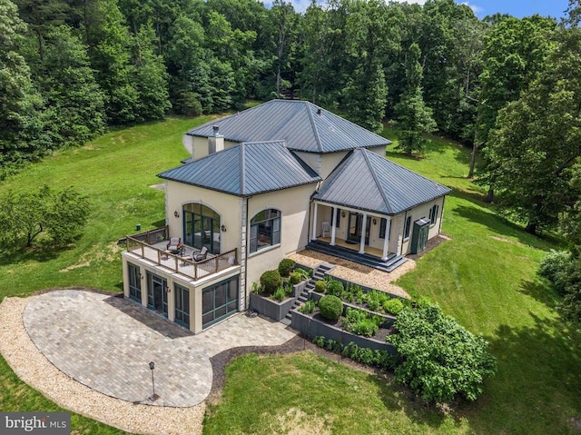 back of property with a yard, a balcony, and a porch