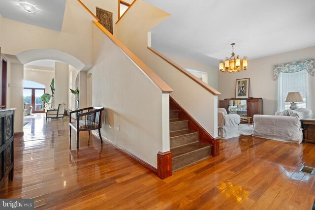 stairway with a chandelier, hardwood / wood-style floors, and a high ceiling