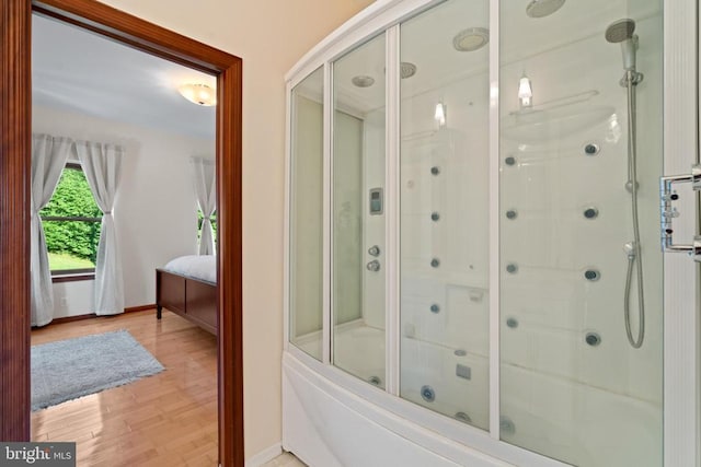 bathroom with hardwood / wood-style flooring and shower / bath combination with glass door