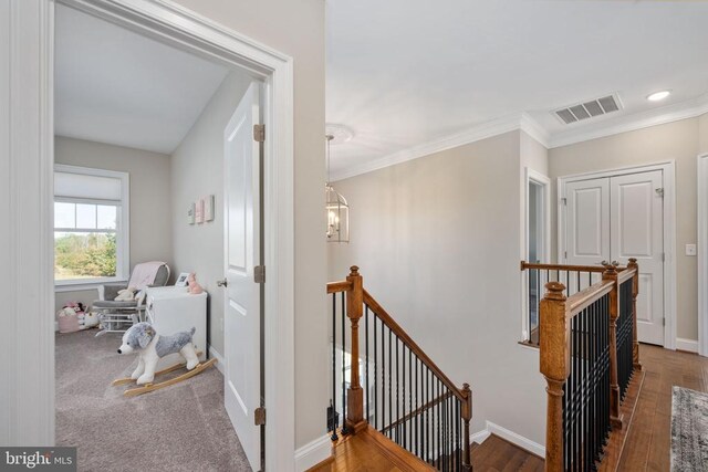 corridor with an inviting chandelier, crown molding, and dark hardwood / wood-style floors