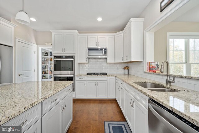 kitchen with pendant lighting, sink, white cabinetry, and appliances with stainless steel finishes