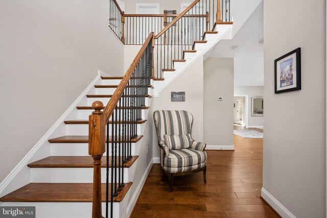 staircase with hardwood / wood-style flooring and a towering ceiling