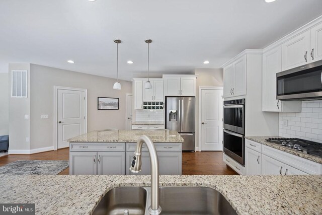 kitchen with light stone counters, hanging light fixtures, white cabinetry, and appliances with stainless steel finishes