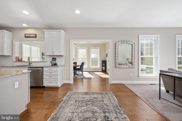 kitchen featuring sink, white cabinetry, light stone counters, dishwasher, and decorative backsplash