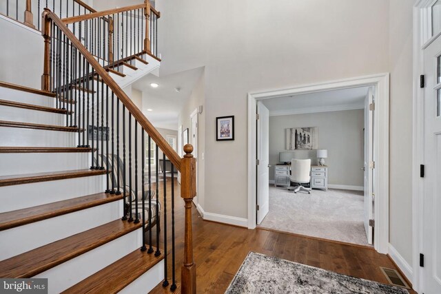 entrance foyer with crown molding, hardwood / wood-style floors, and a towering ceiling