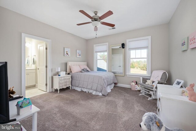 bedroom featuring ceiling fan, light colored carpet, and ensuite bath