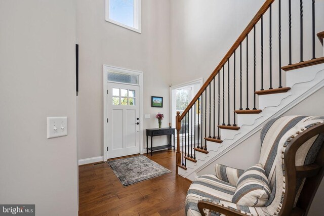 foyer with dark hardwood / wood-style flooring and a towering ceiling